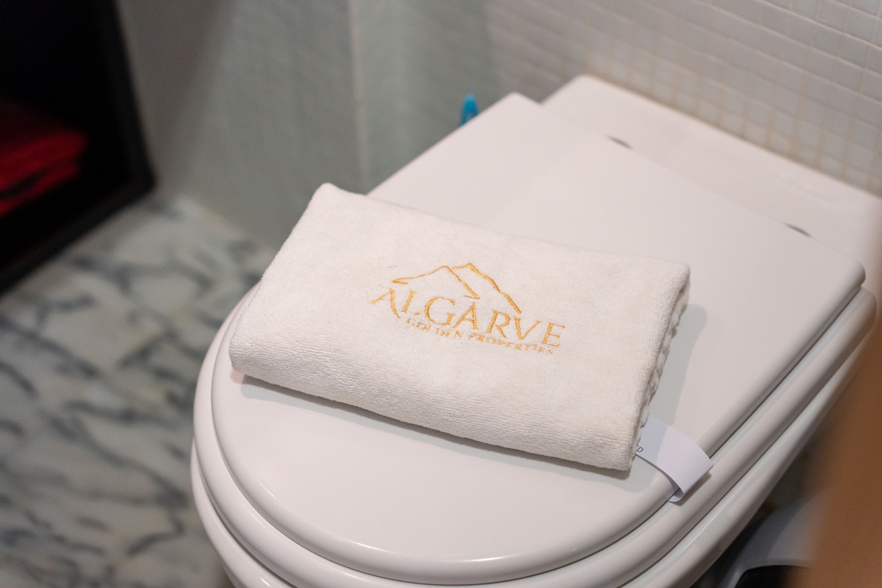 A white toilet with a towel on top and the text 'ALGARVE' on it.