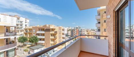 A balcony with a view of neighboring buildings and parked cars.