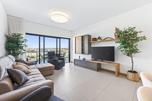 A modern living room with a sofa, TV, and potted plants. - Marina Village Retreat Pool Garage Prime lo (Lagos)