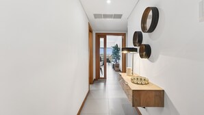 A hallway with a wooden floor, a light fixture, and a wall-mounted mirror. - Marina Village Retreat Pool Garage Prime lo (Lagos)