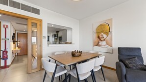 A modern dining area with a wooden table, white chairs, and a grey sofa. - Marina Village Retreat Pool Garage Prime lo (Lagos)