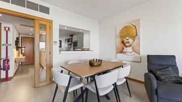 A modern dining area with a wooden table, white chairs, and a grey sofa.