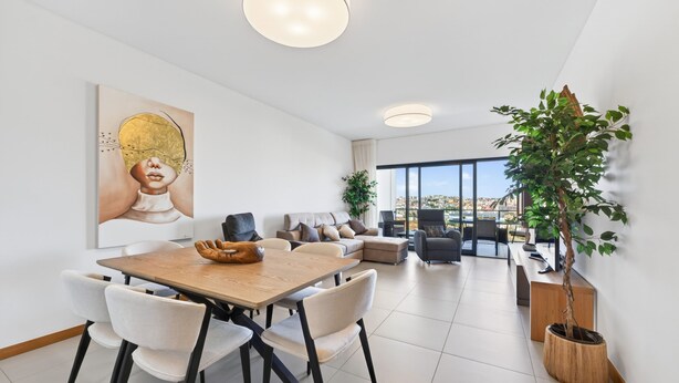 A modern living room with a dining area, a large window, and a view of the city. - Marina Village Retreat Pool Garage Prime lo (Lagos)