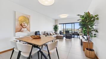 A modern living room with a dining area, a large window, and a view of the city.