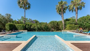 A rectangular swimming pool with clear blue water, surrounded by palm trees and lush greenery. - Marina Village Retreat Pool Garage Prime lo (Lagos)