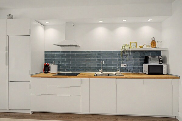 A modern kitchen with white cabinetry, a wooden countertop, a built-in stove, and a microwave.