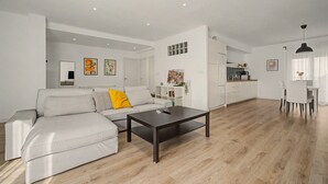 A modern living room with a sofa, a coffee table, and a dining area with chairs.