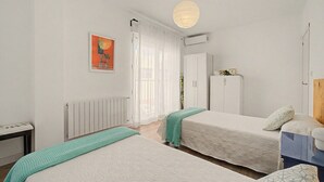 A room with two beds, a radiator, a wardrobe, and a painting on the wall.