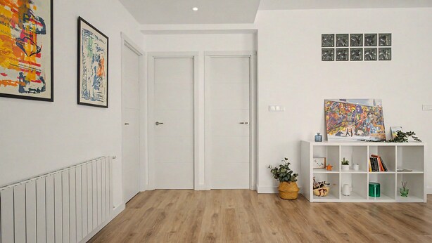 A hallway with a white radiator, two white doors, a white shelving unit with books and decorative items, and a framed abstract painting on the wall.