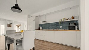 A modern kitchen with white cabinetry, a wooden countertop, and a black pendant light.