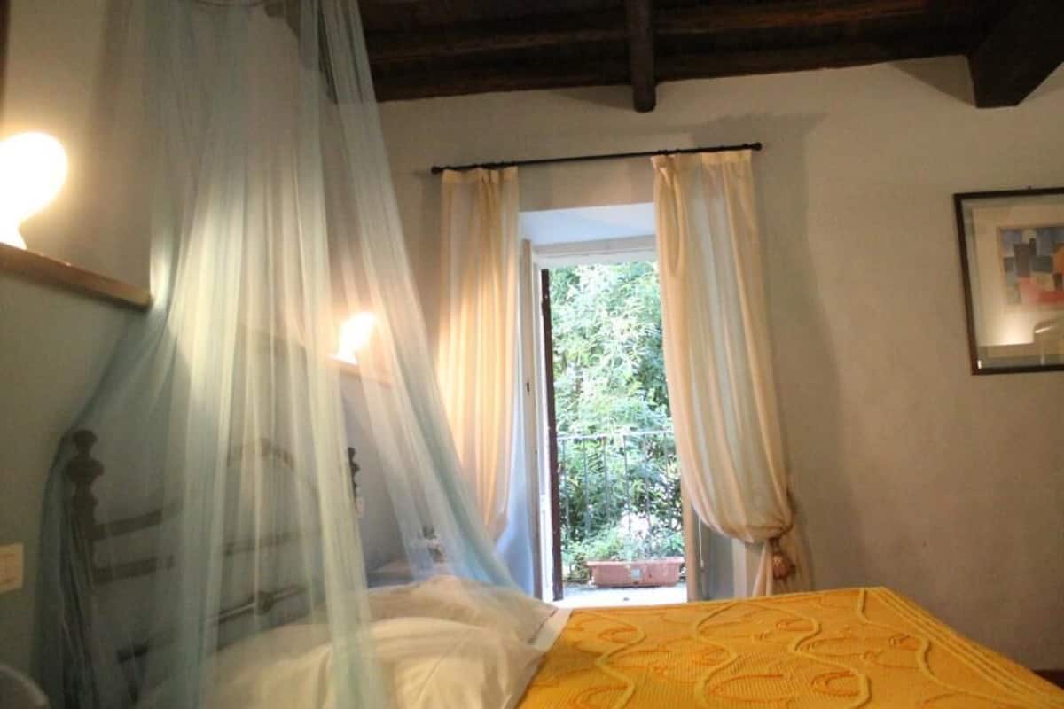 Une chambre à coucher avec un lit, une fenêtre avec des rideaux et une vue sur la verdure à l’extérieur.