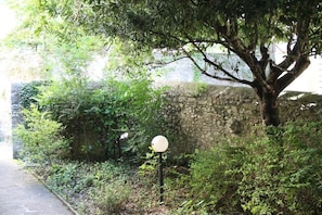 Un mur de pierres, un arbre et un panneau indicateur, le tout dans un environnement naturel.