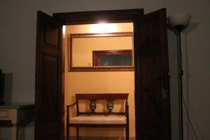 Una habitación con un banco de madera, un espejo y una lámpara.