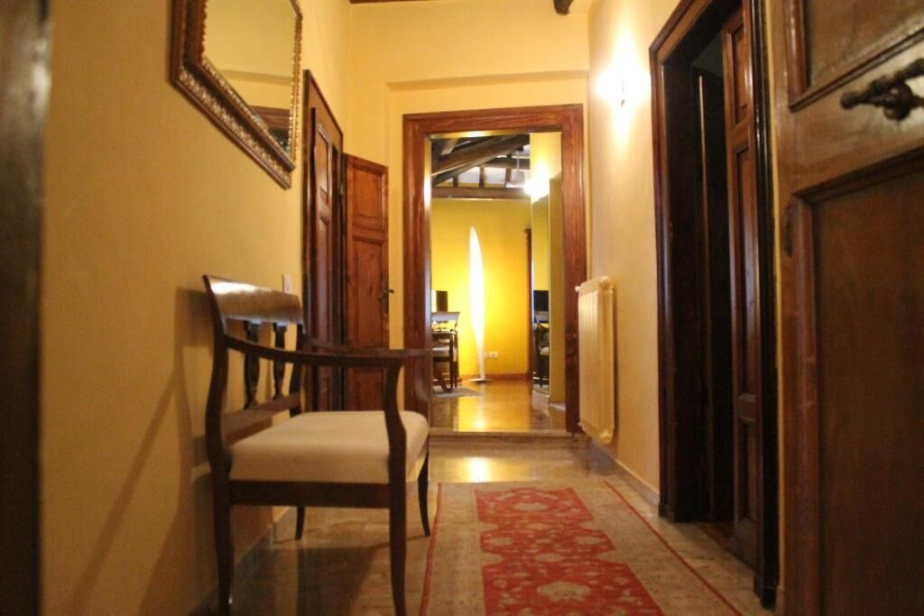 A hallway with a wooden chair, a red carpet, and wooden doors.