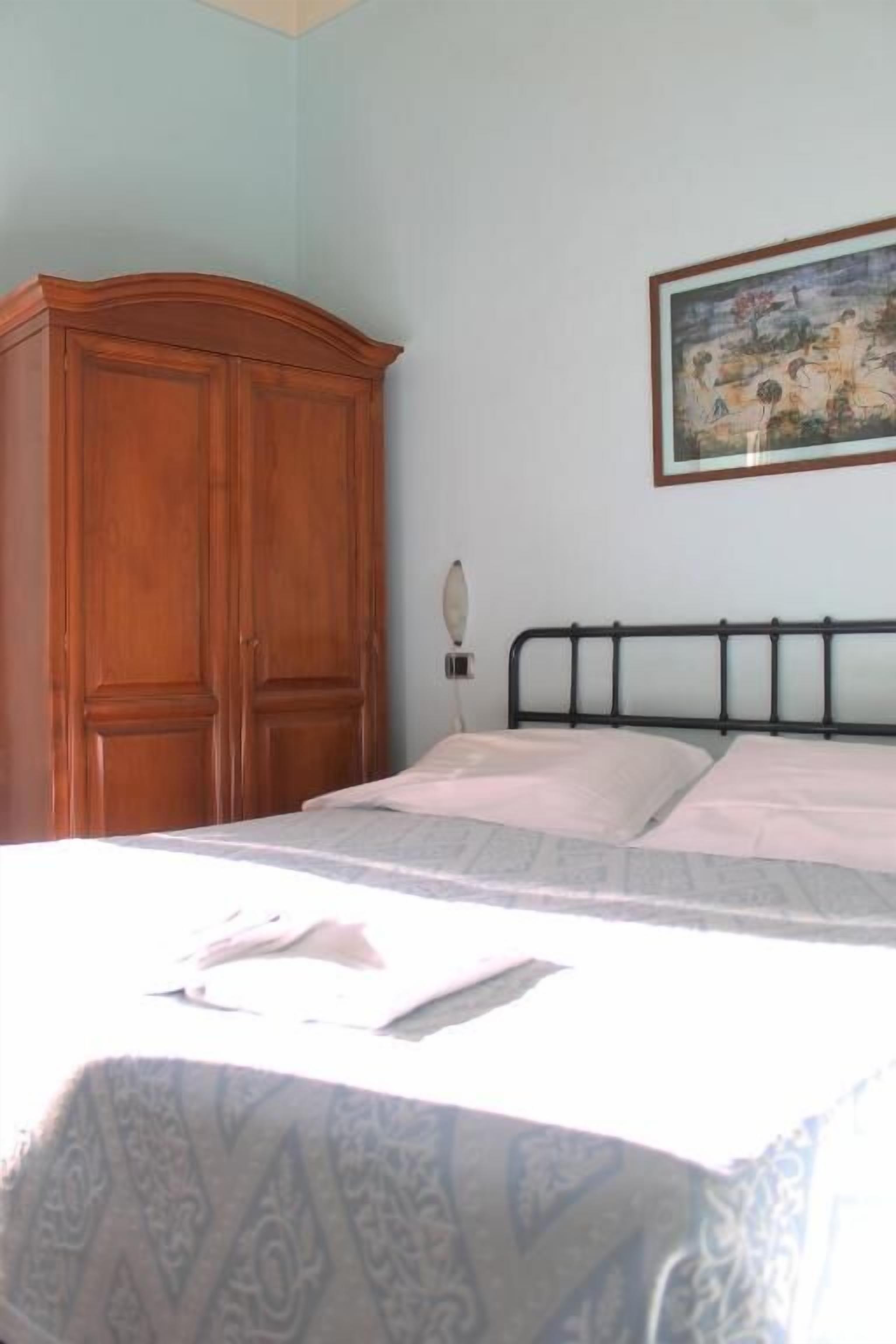 Un dormitorio con cama, armario de madera y un cuadro en la pared.