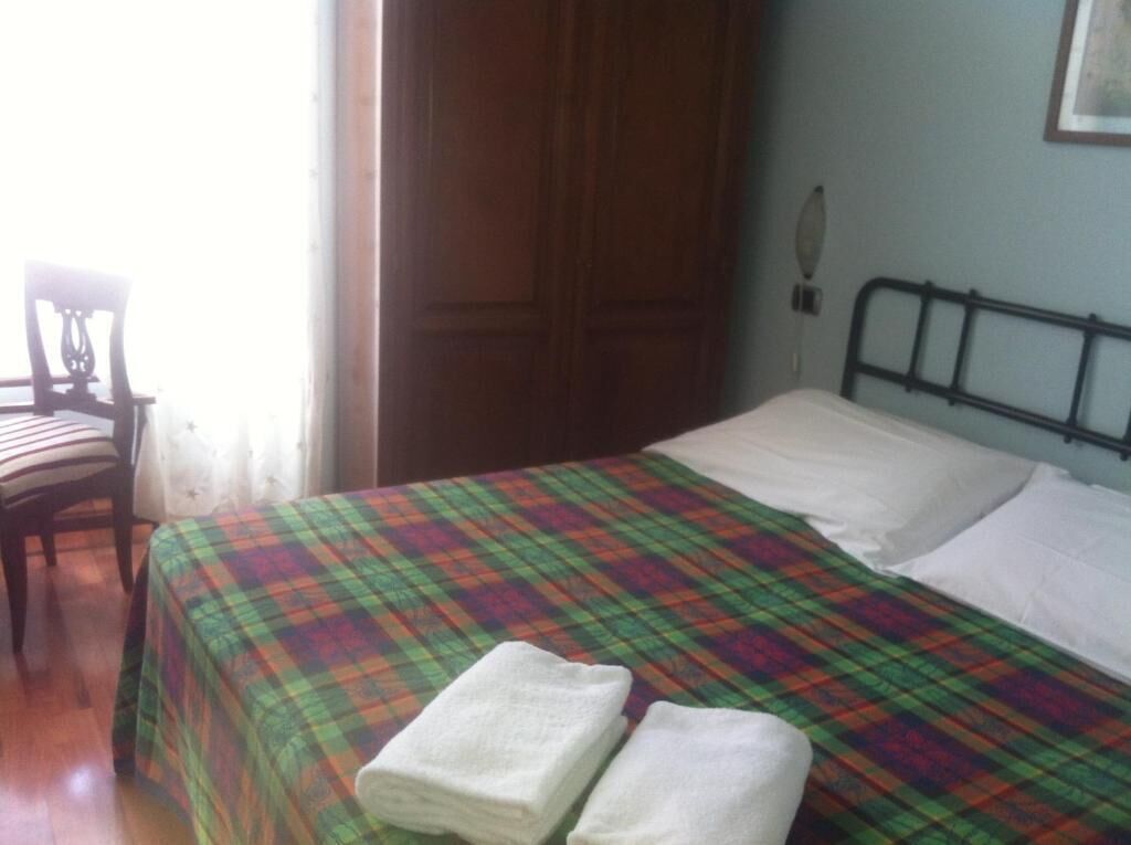 Una habitación con una cama, una silla y una puerta.