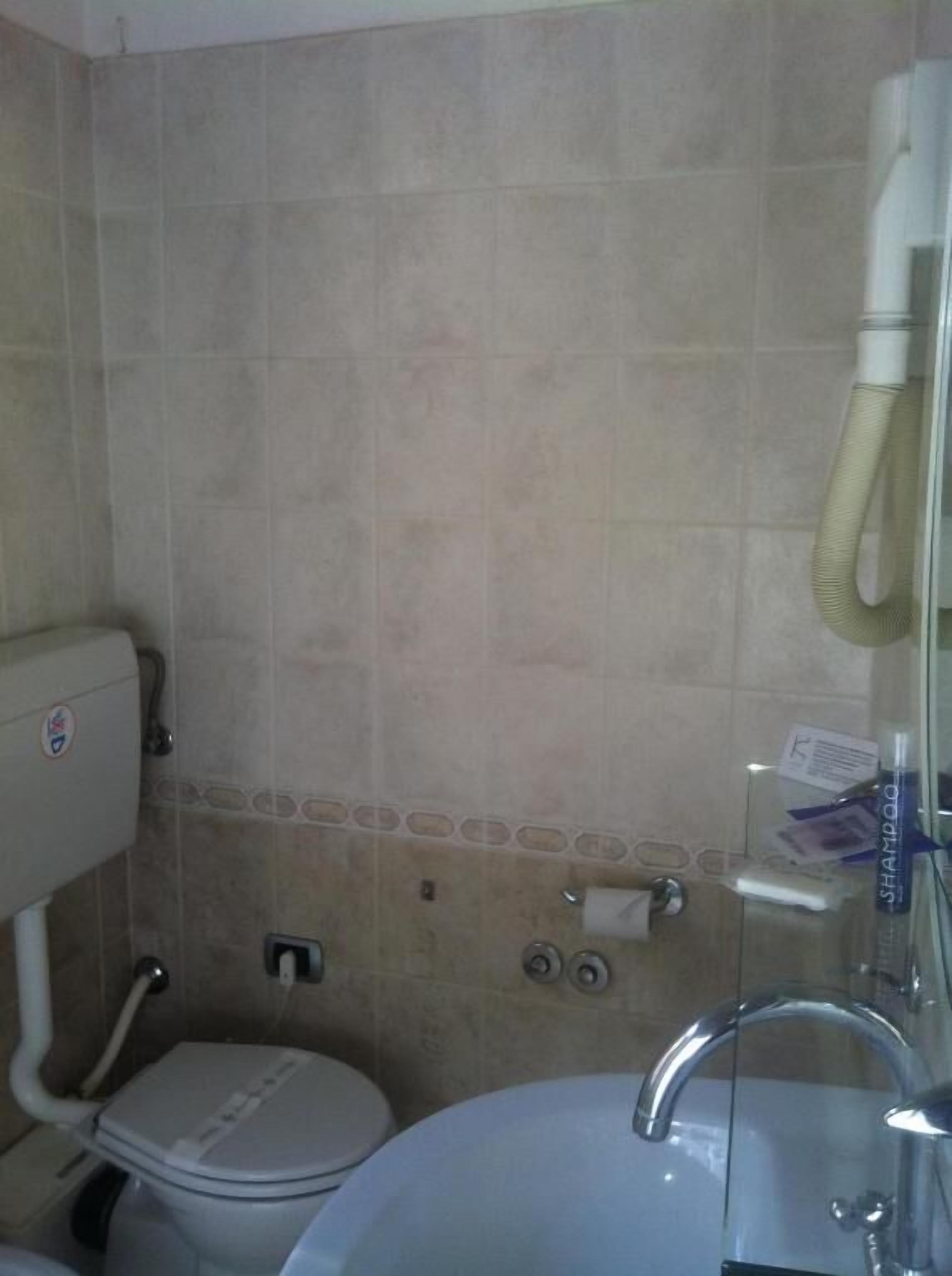 A bathroom with a toilet, sink, and shower.