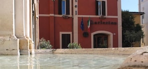 Un hôtel à la façade rouge, avec une entrée bien visible et deux drapeaux.