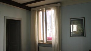 Et værelse med et vindue, en radiator og et billede i ramme på væggen.