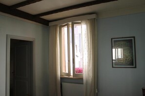 Une pièce avec une fenêtre, un radiateur et un tableau encadré au mur.