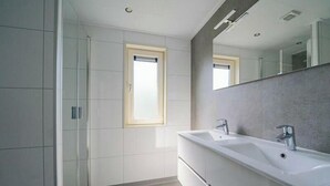 A modern bathroom with a large mirror, two sinks, and a shower. - Pavilion Waterfront 8 (Linden)