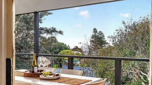 Un balcon avec une table dressée pour deux personnes, une bouteille de champagne et un panier de fruits.