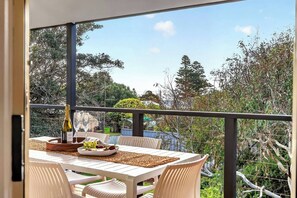 A balcony with a table set for two, a bottle of champagne, and a bowl of fruit. - The Sellicks Perch Unique Drive On Beach Adventure (Sellicks Beach)