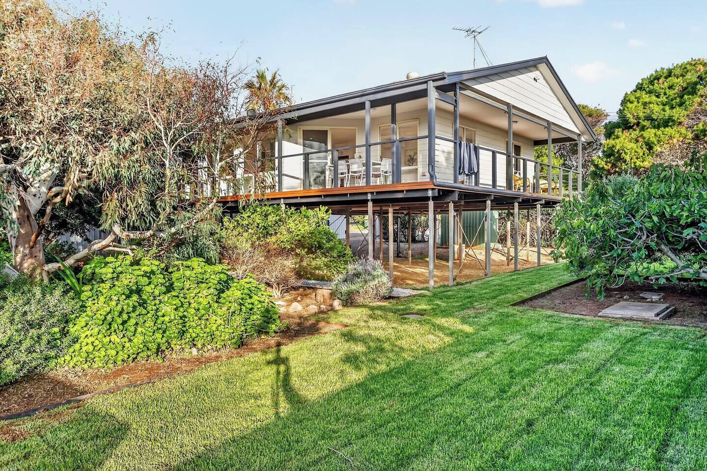 The backyard adds another layer of outdoor space, with established greenery creating a peaceful setting beneath the elevated home.