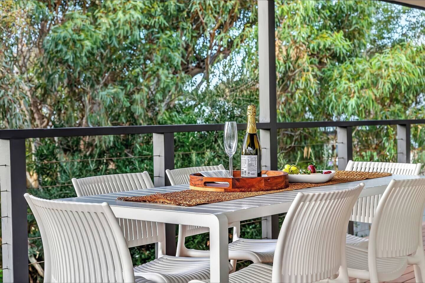 Un espace extérieur aménagé pour prendre les repas, avec une table dressée pour deux personnes, entourée de chaises blanches.