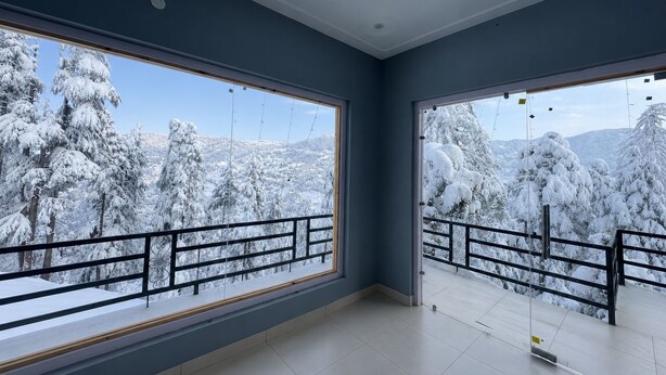 Quarto com amplas janelas e vista para uma montanha nevada.