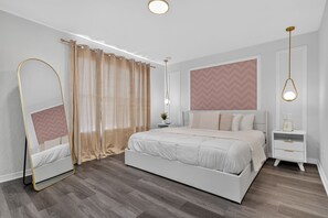 A modern bedroom with a large bed, a bedside table, a nightstand, a mirror, and a hanging light fixture. - Family Retreat: 4BR Home with Private Spa (Kissimmee)