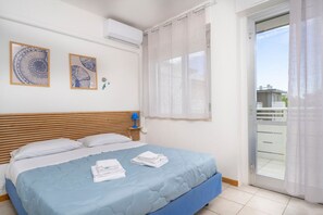 A bedroom with a bed, a window with curtains, and two wall-mounted artworks. - GuestHost - La Casa al Mare APT 406 with Parking (Lignano Sabbiadoro)