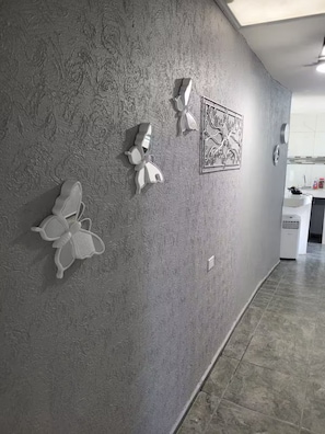 Un couloir aux murs texturés, orné d’une œuvre d’art en métal à motifs, et équipé d’un climatiseur blanc.