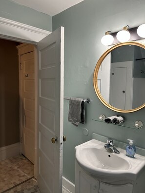 Un bagno con un lavandino bianco, uno specchio con cornice dorata e un asciugamano su un portascopevoli.