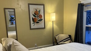A hotel room with a bed, a lamp, a framed picture on the wall, and a window with curtains. - Bright apartment in quaint Fargo with refreshing AC (Fargo)