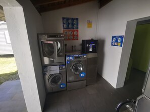 A laundry facility with three washing machines, a drying machine, and a control panel.