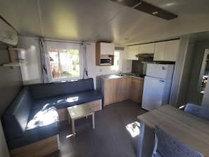 Une cuisine compacte équipée d’un four à micro-ondes encastré, d’un évier et d’une cuisinière. Un coin salon avec un canapé et une petite table est également disponible.