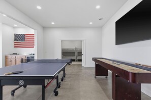 A room with a ping pong table, foosball table, and a television on the wall. - Duck Creek Overlook. Premium Location. All the Amenities! (Afton)