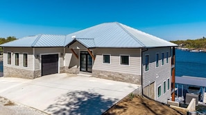 A two-story house with a garage, a covered porch, and a view of the water. - Duck Creek Overlook. Premium Location. All the Amenities! (Afton)