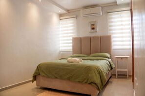 Um quarto com uma cama, uma mesa de cabeceira e um ar condicionado.