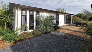 A single-story house with a patio area, a small garden, and a gravel driveway. - Comfort 4 Persons (Egmond aan den Hoef)