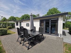 Eine Terrasse mit Tisch und Stühlen, einem Sonnenschirm und einer Glasglastür, die zu einem Poolbereich führt.