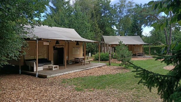 Two rustic cabins with wooden structures, each featuring a porch and a picnic table. - Holiday Home in Otterlo With Terrace (Otterlo)