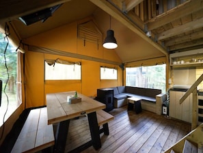 Ein gemütliches Interieur mit Holztisch, Sitzbank, einer Pendelleuchte und einer Treppe, die in eine obere Ebene führt.