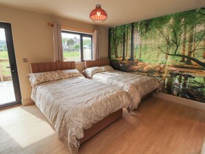 A bedroom with two beds, a large window, and a forest mural. - Beckdale (Settle)