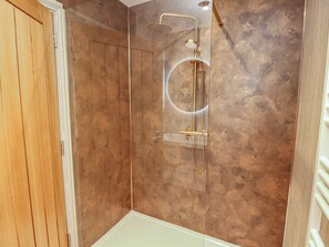Eine Dusche mit Glastrennwand und Handbrause.