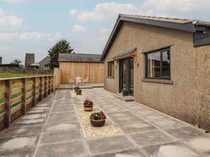 A patio with stone flooring, wooden fence, and potted plants. - Beckdale (Settle)