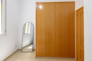 Ein Zimmer mit großem Holzschrank, einem Spiegel und einem Fenster.