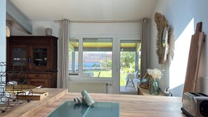 Una habitación con una mesa de madera, un tapete, un armario, un ventanal y vistas al exterior.