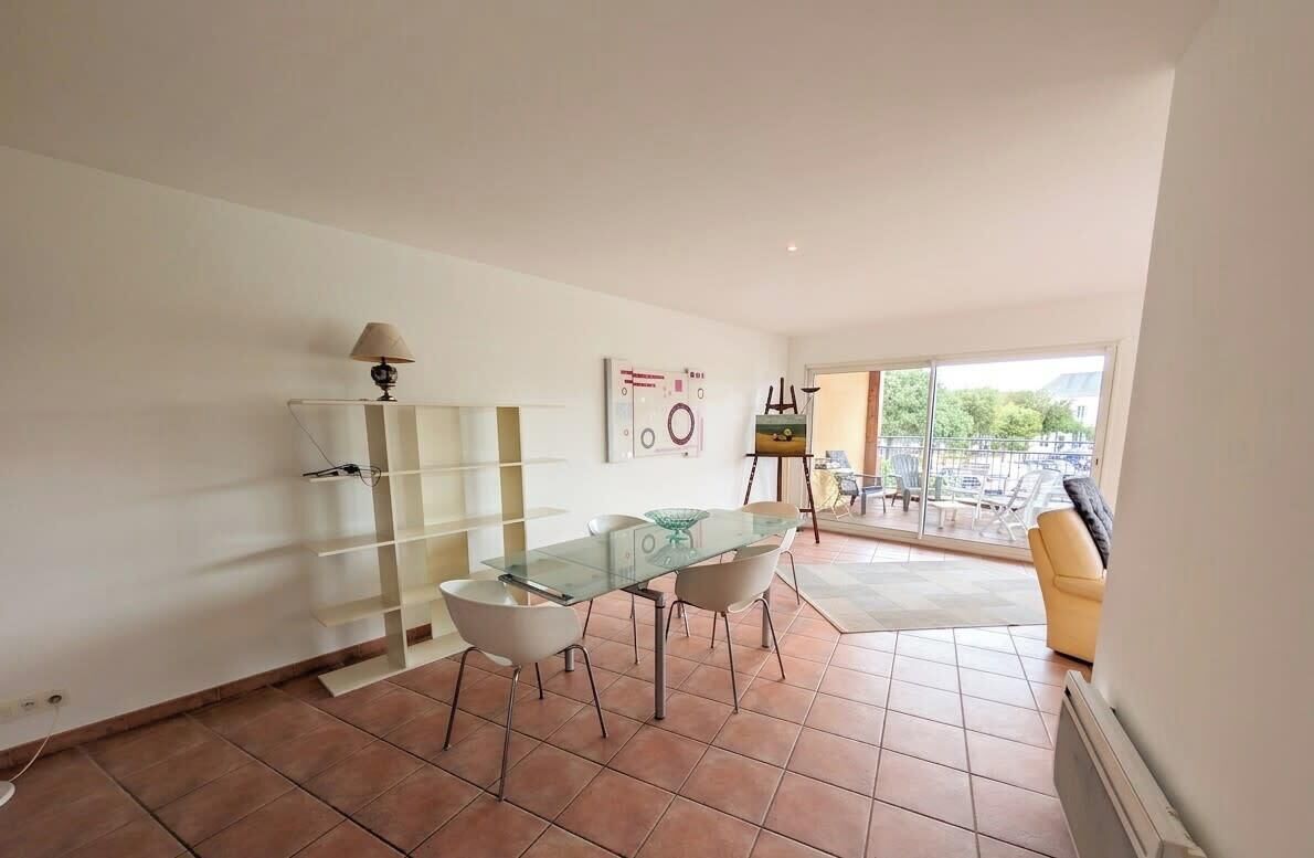 A dining area with a glass table and chairs, a lamp, and a painting on the wall.